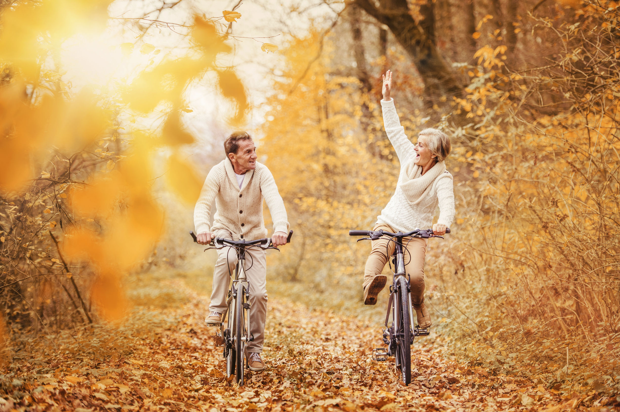 active seniors ridding bike in autumn nature. they having fun outdoor.